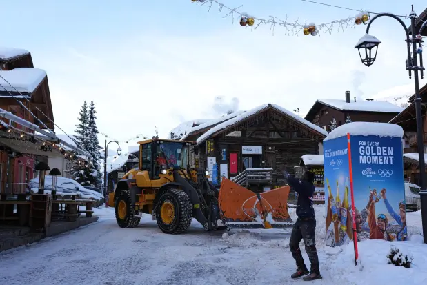 A man takes a photo as a worker plows snow at the 2026 Winter Olympics, in Livigno, Italy, Thursday, Feb. 5, 2026. (AP Photo/Andy Bao)