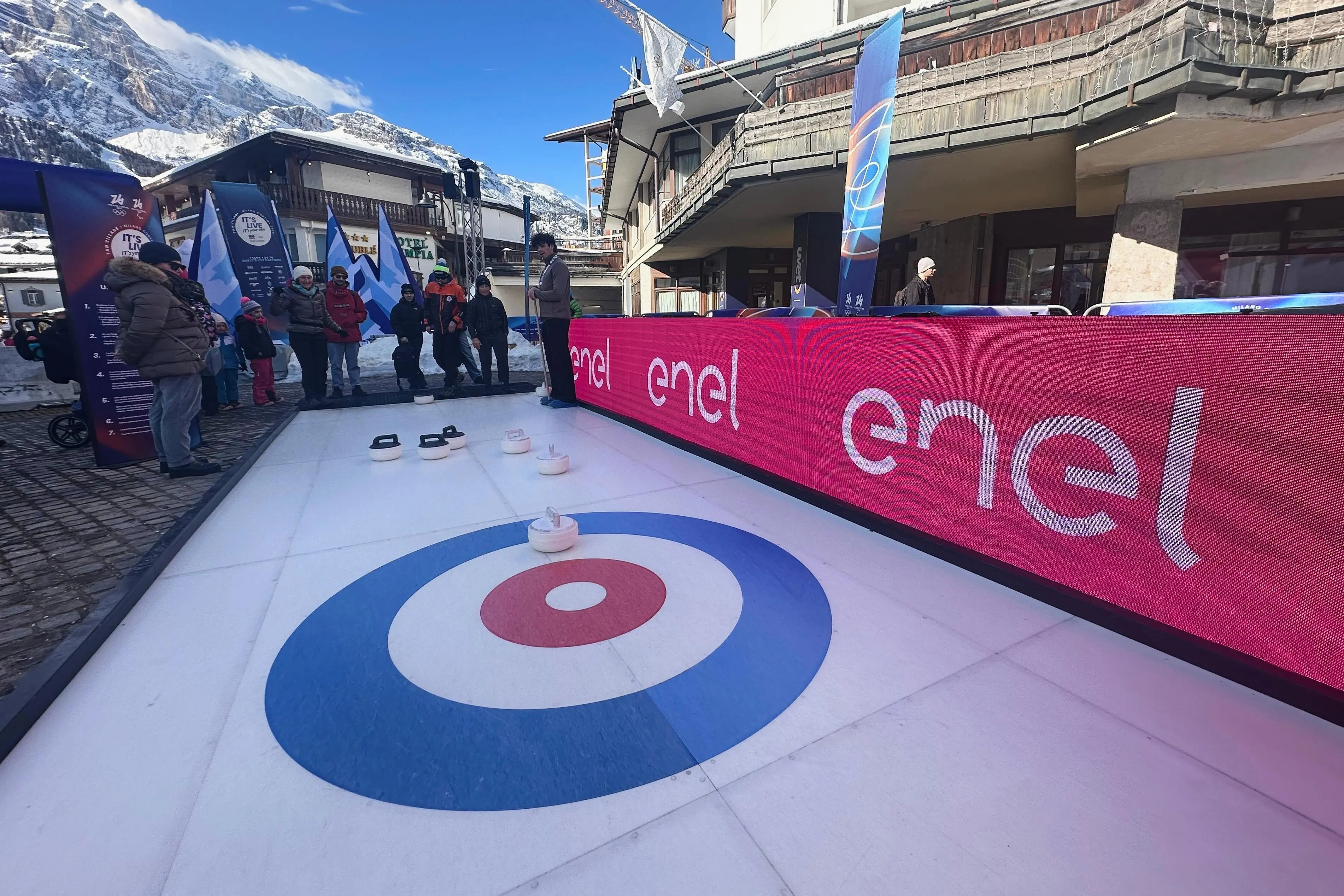 Olympic fans try curling next to signage for Enel at...