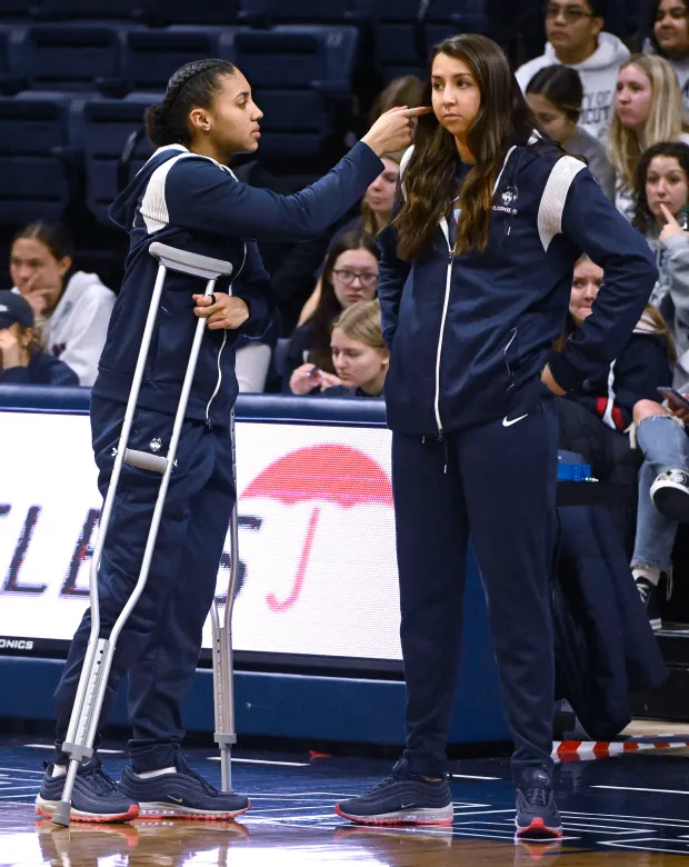 UConn's Azzi Fudd, left, reaches to adjust teammate Caroline Ducharme's hair as the team warms up with out them before an NCAA college basketball game against Butler, Saturday, Jan. 21, 2023, in Storrs, Conn. Fudd is out with a knee injury and Ducharme is on a concussion protocol. (AP Photo/Jessica Hill)