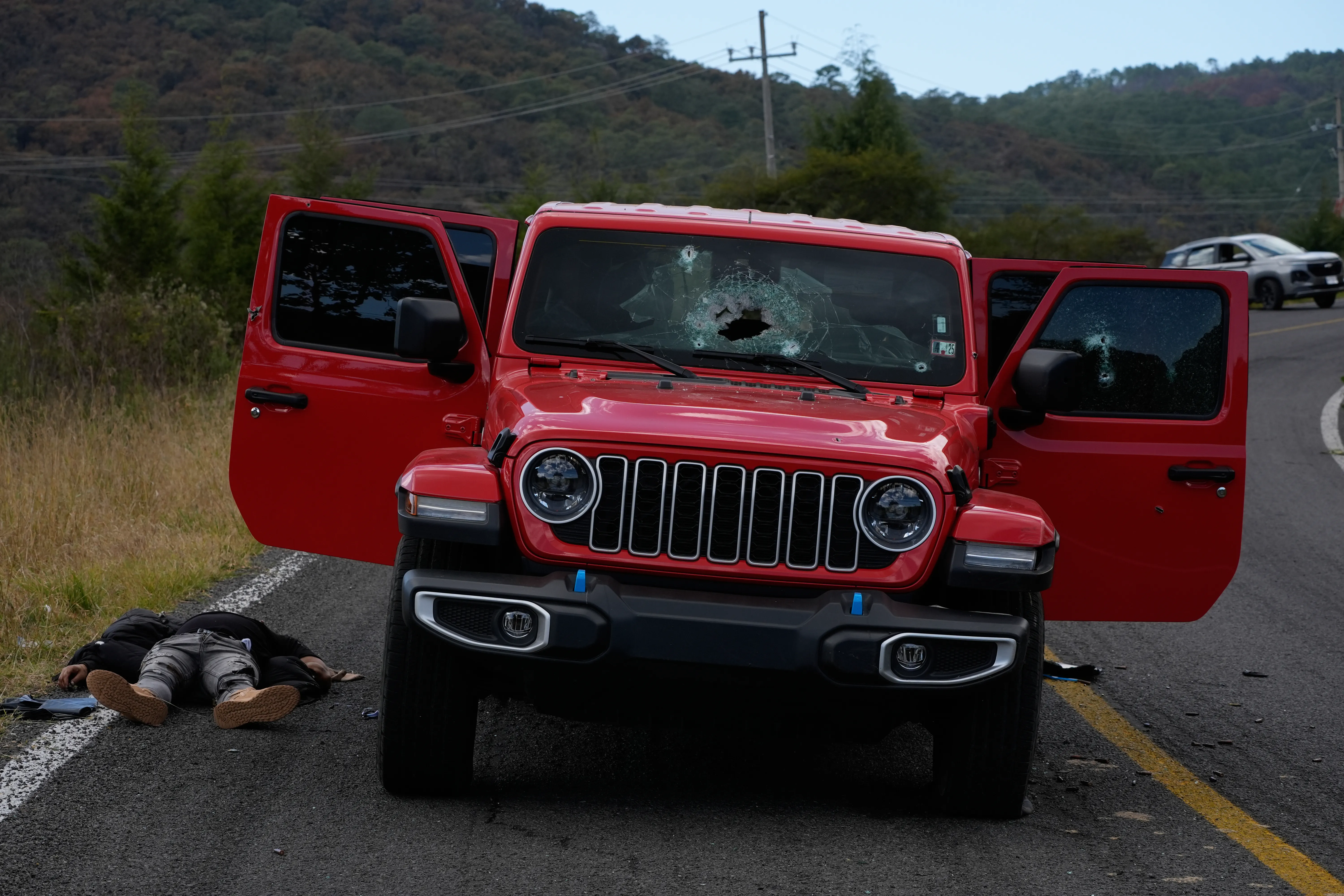 A body lies beside a bullet-riddled vehicle in Tapalpa, Mexico.