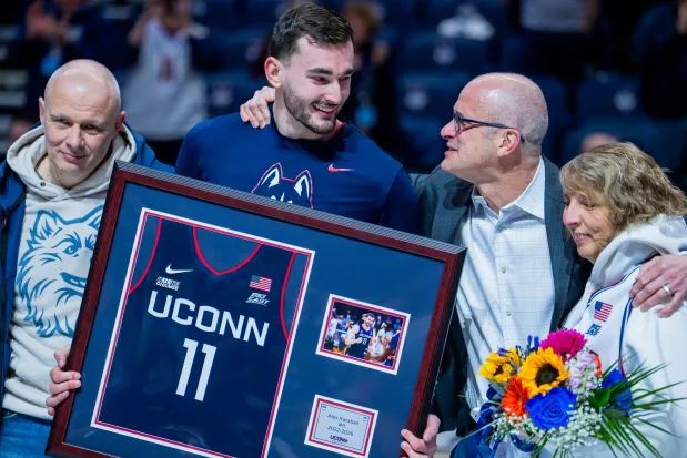 With dad, Alexei, left, and mom, Olga, right, UConn's Alex Karaban gets a hug from his coach, Dan Hurley on Saturday at Gampel Pavilion. (Joe Buglewicz/Getty Images)