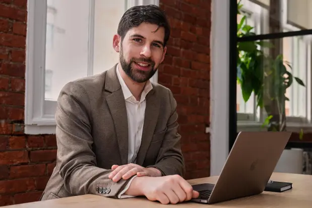 Udio CEO Andrew Sanchez sits with a laptop at a table.