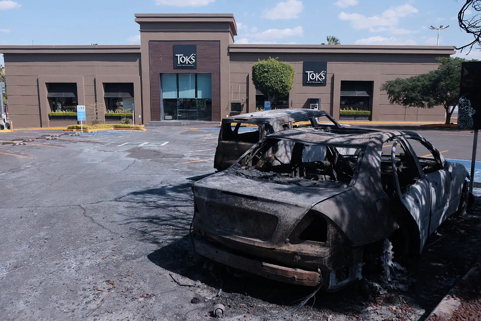 Charred vehicles sit in a parking lot outside a shopping mall in Guadalajara.