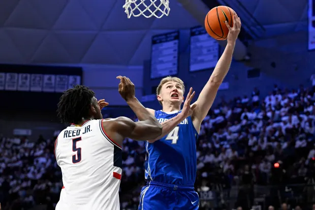 Creighton guard Josh Dix (4) goes up for a basket as UConn forward Tarris Reed Jr. (5) defends in the first half of an NCAA college basketball game, Wednesday, Feb. 18, 2026, in Storrs, Conn. (AP Photo/Jessica Hill)