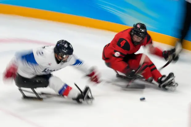 James Dunn of Canada battles for the puck against South Korea's Kim Young-sung during their para ice hockey match.