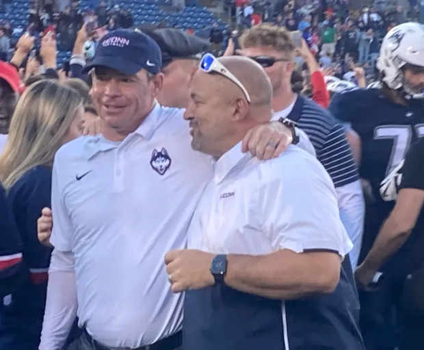 UConn coach Jim Mora (left) and AD David Benedict walk off the field after beating Liberty to clinch bowl eligibility on Nov. 12. On Sunday, they learned their destination, Myrtle Beach, S.C., to play Marshall. (Dom Amore/Hartford Courant)..