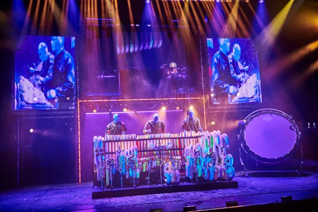 Percussive music is at the core of all Blue Man Group shows. This tour features a separate character, a female musician called The Rock Star. (Martin Girard)