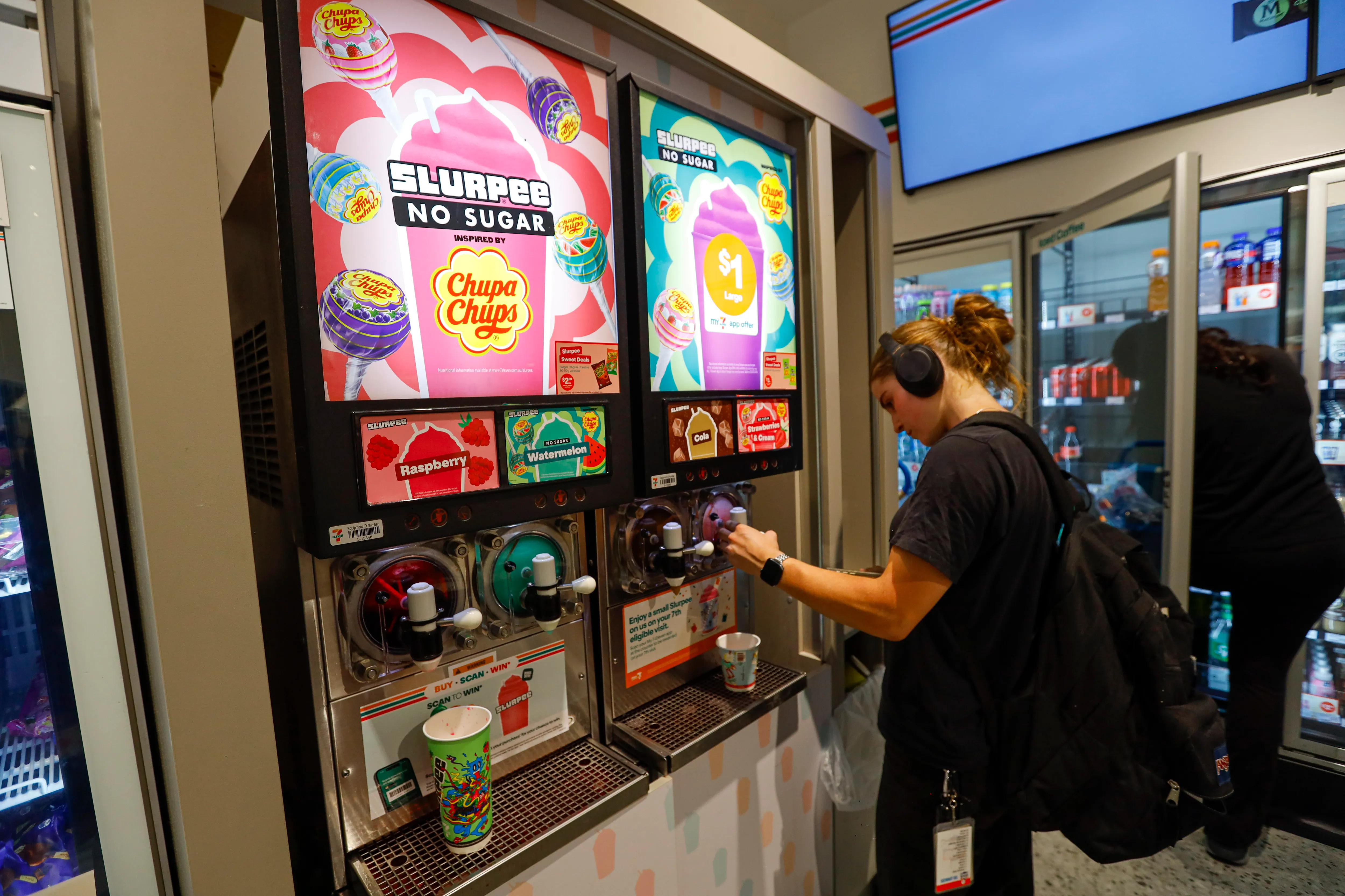 A woman seen filling a cup from a Slurpee machine at a 7-Eleven store